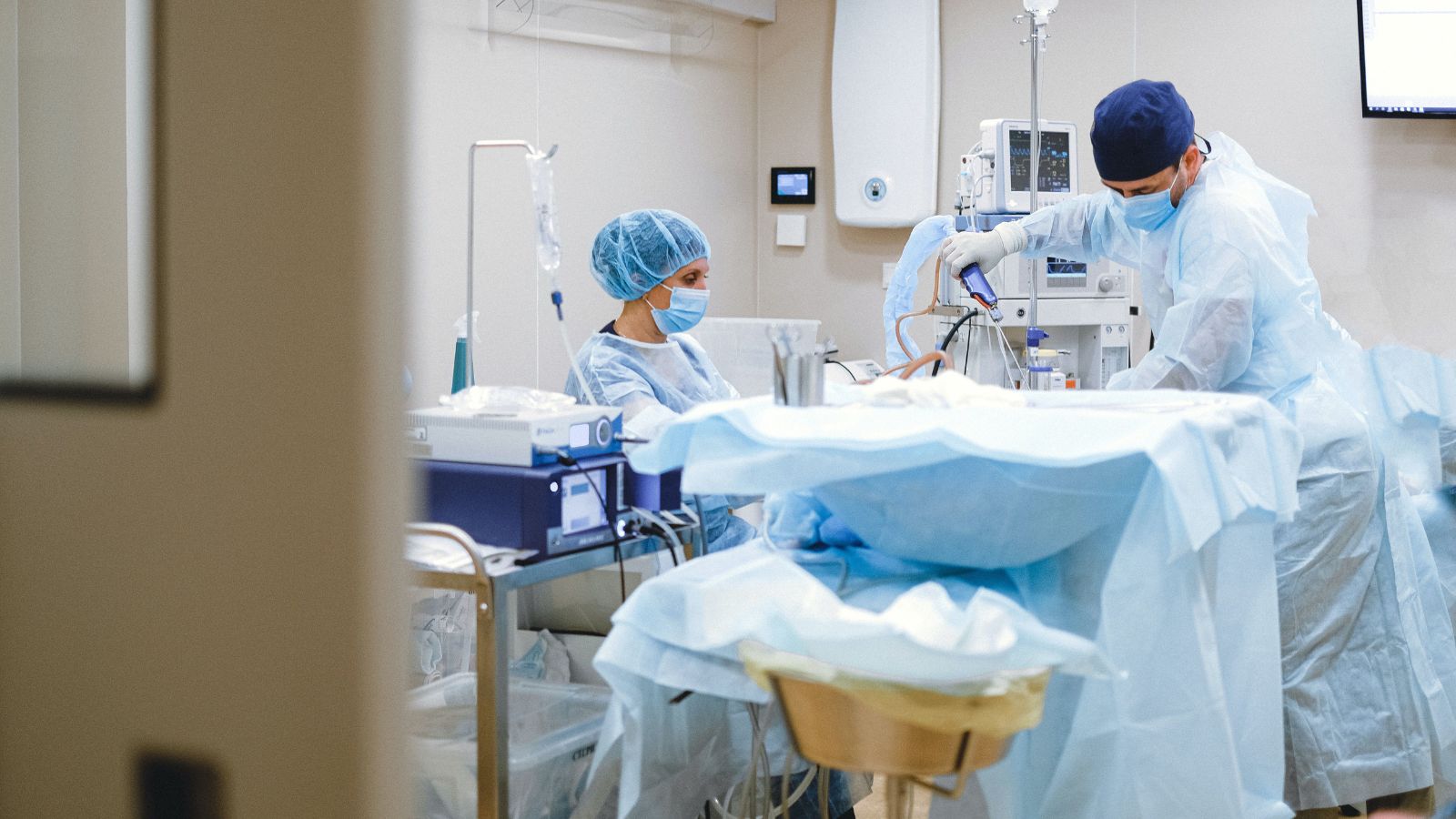 A surgeon and a nurse in scrubs and masks at work in a hospital operating room